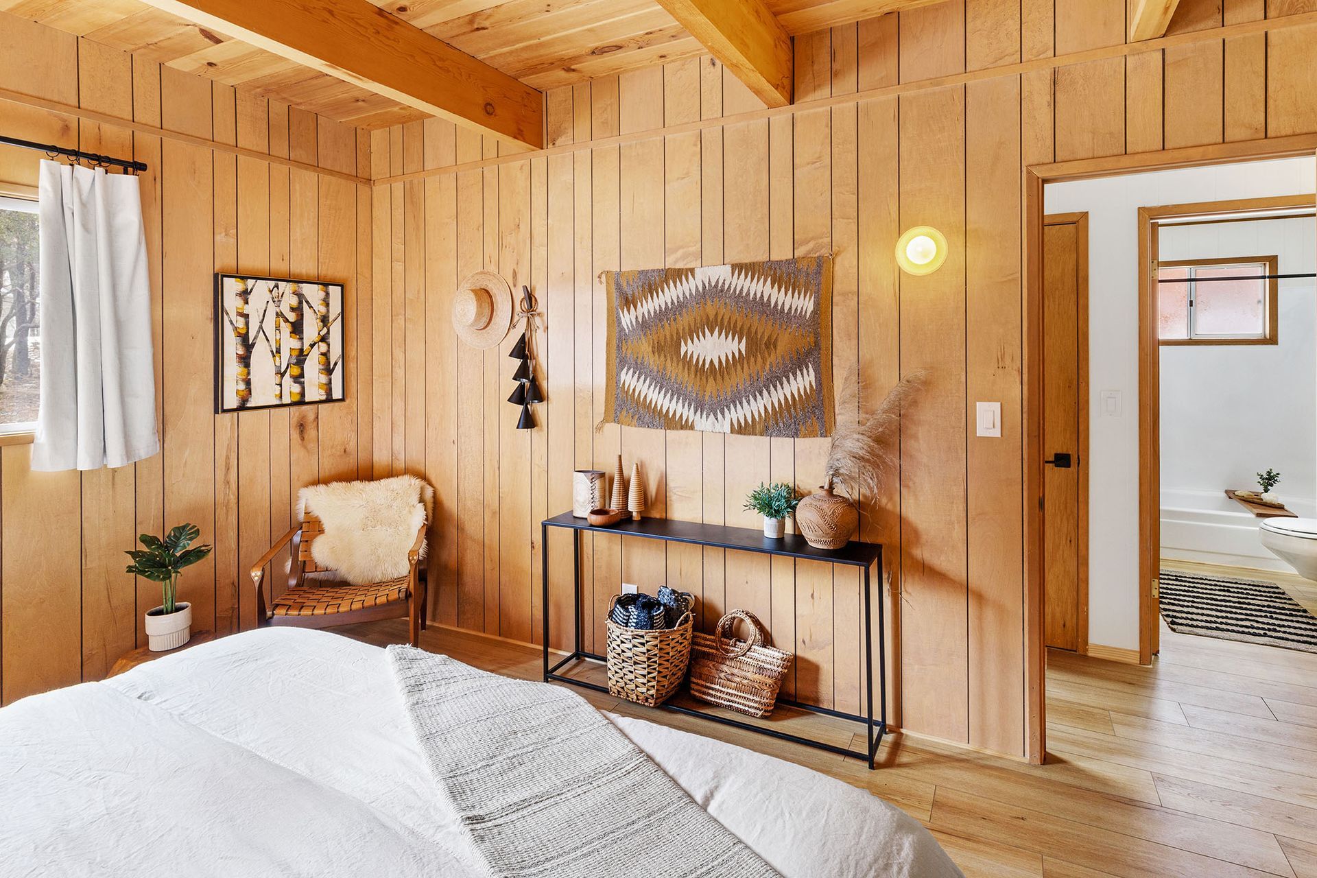 A bedroom with wood paneling , a bed , a chair and a table.