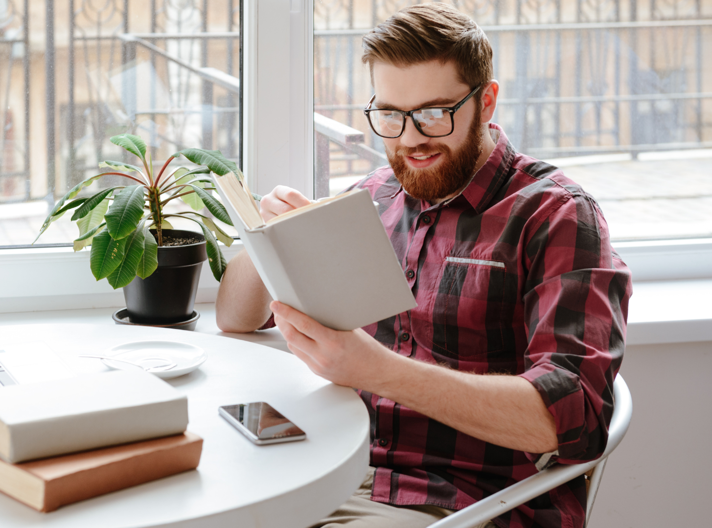 A man is sitting at a table reading a book.