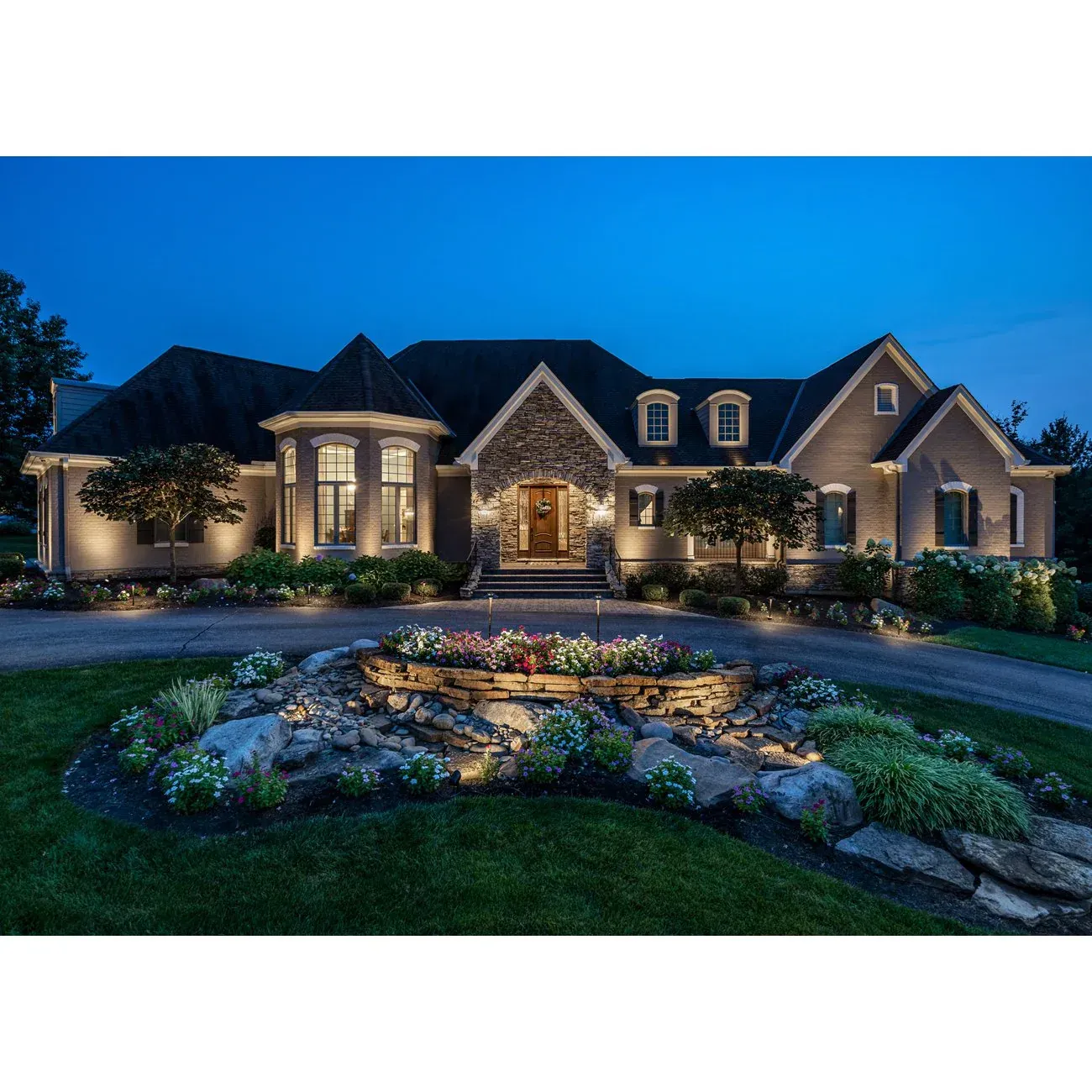 A sprinkler sprays water in a fan shape over a lush green lawn during a sunny day.