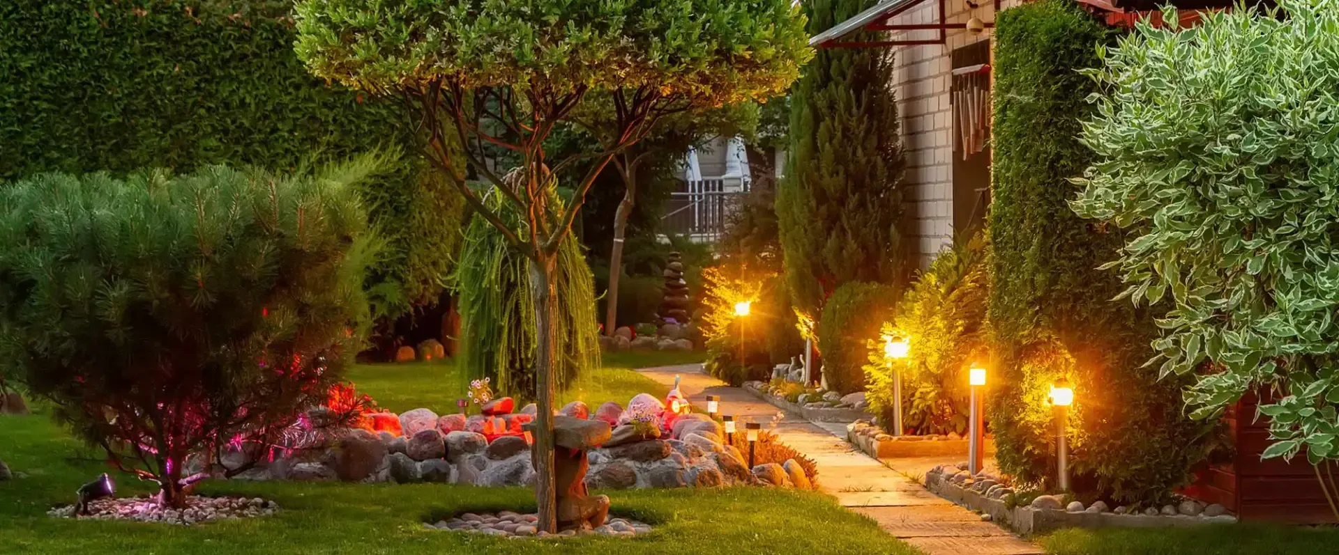 A sprinkler sprays water in a fan shape over a lush green lawn during a sunny day.