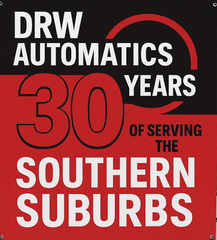 A man is smiling while working on a car in a garage.