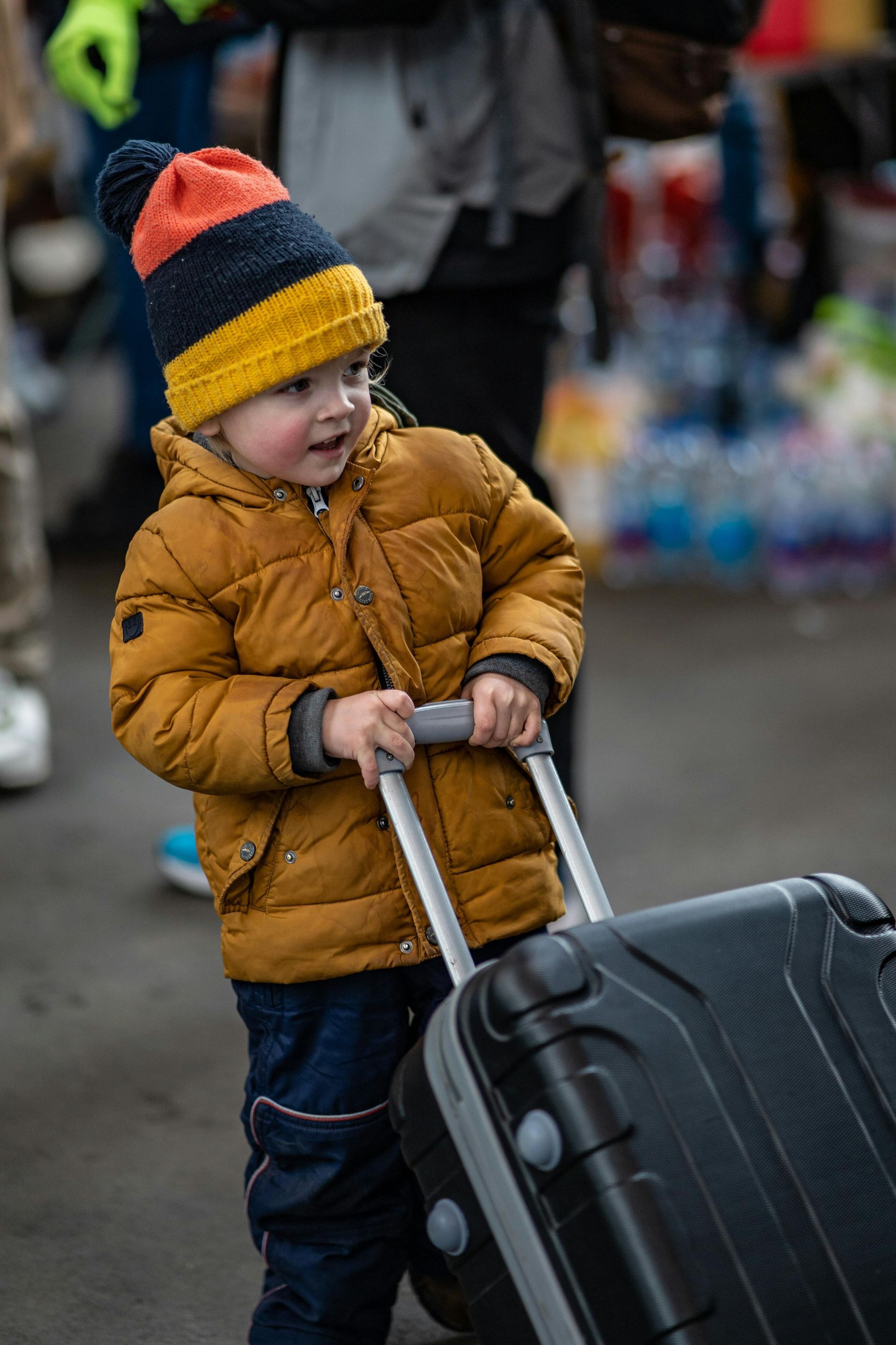 A little boy is pulling a suitcase on a trolley.