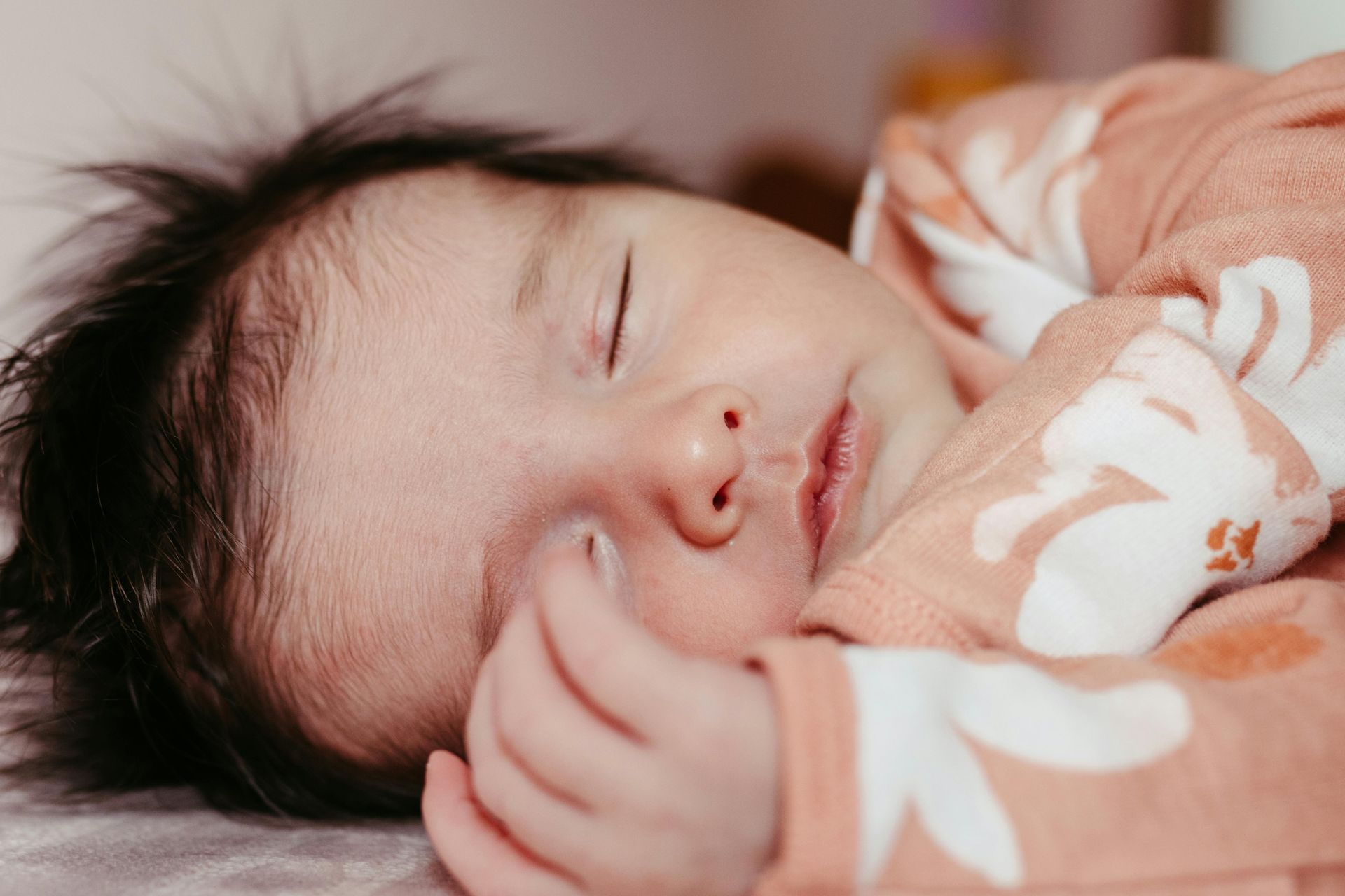 A close up of a baby sleeping on a bed.