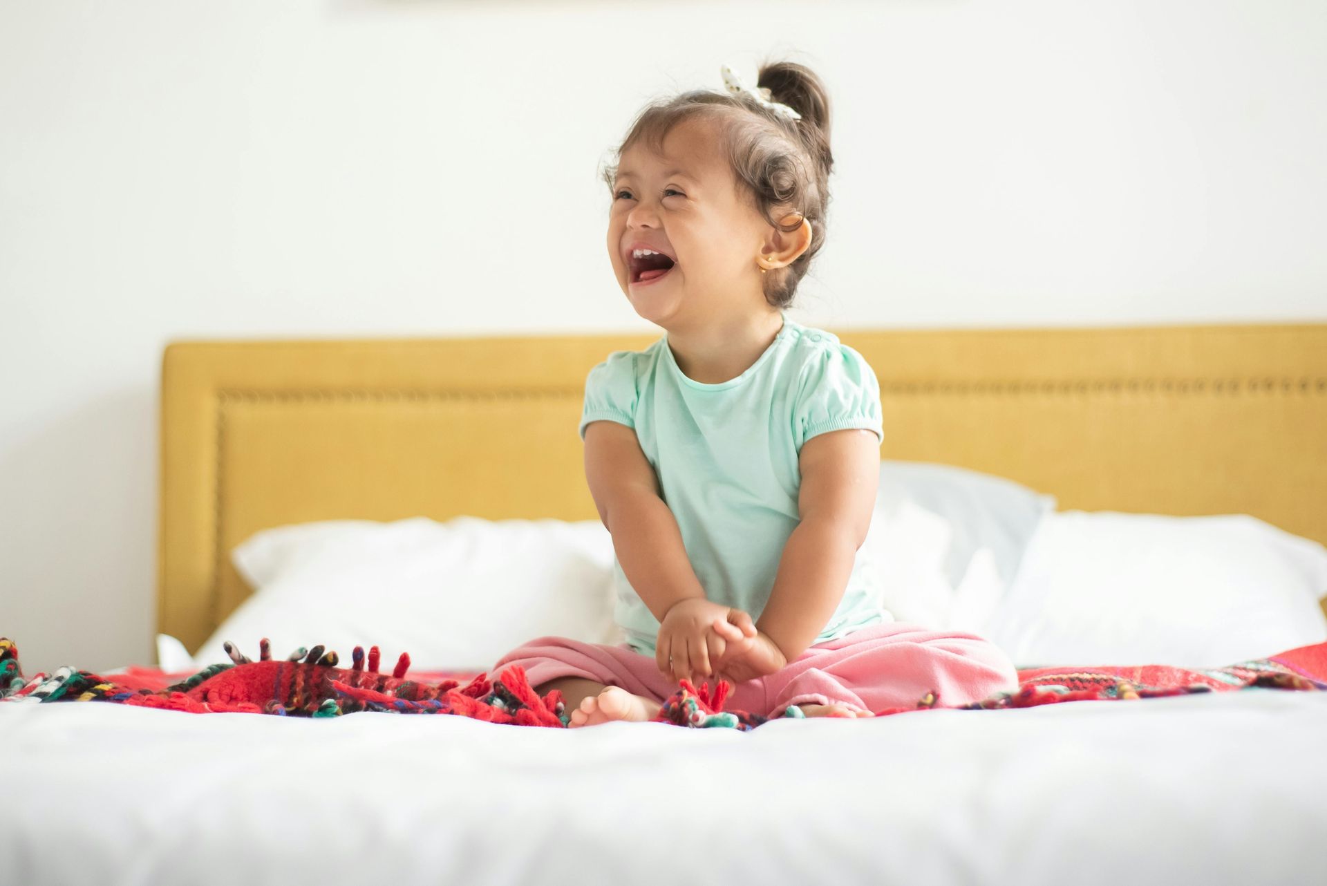 A little girl is sitting on a bed playing with toys.
