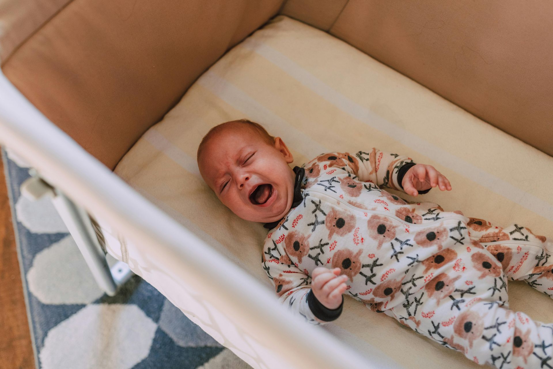 A baby is crying while laying in a crib.