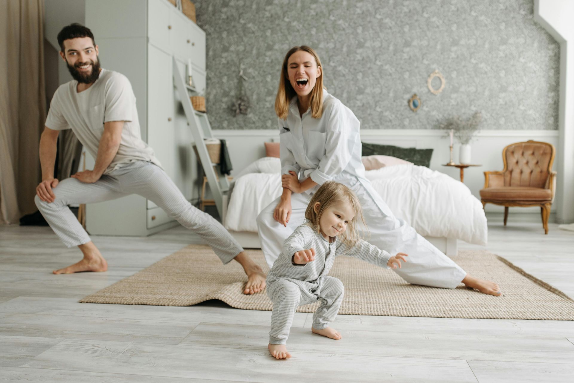 A family is doing yoga together in a bedroom.