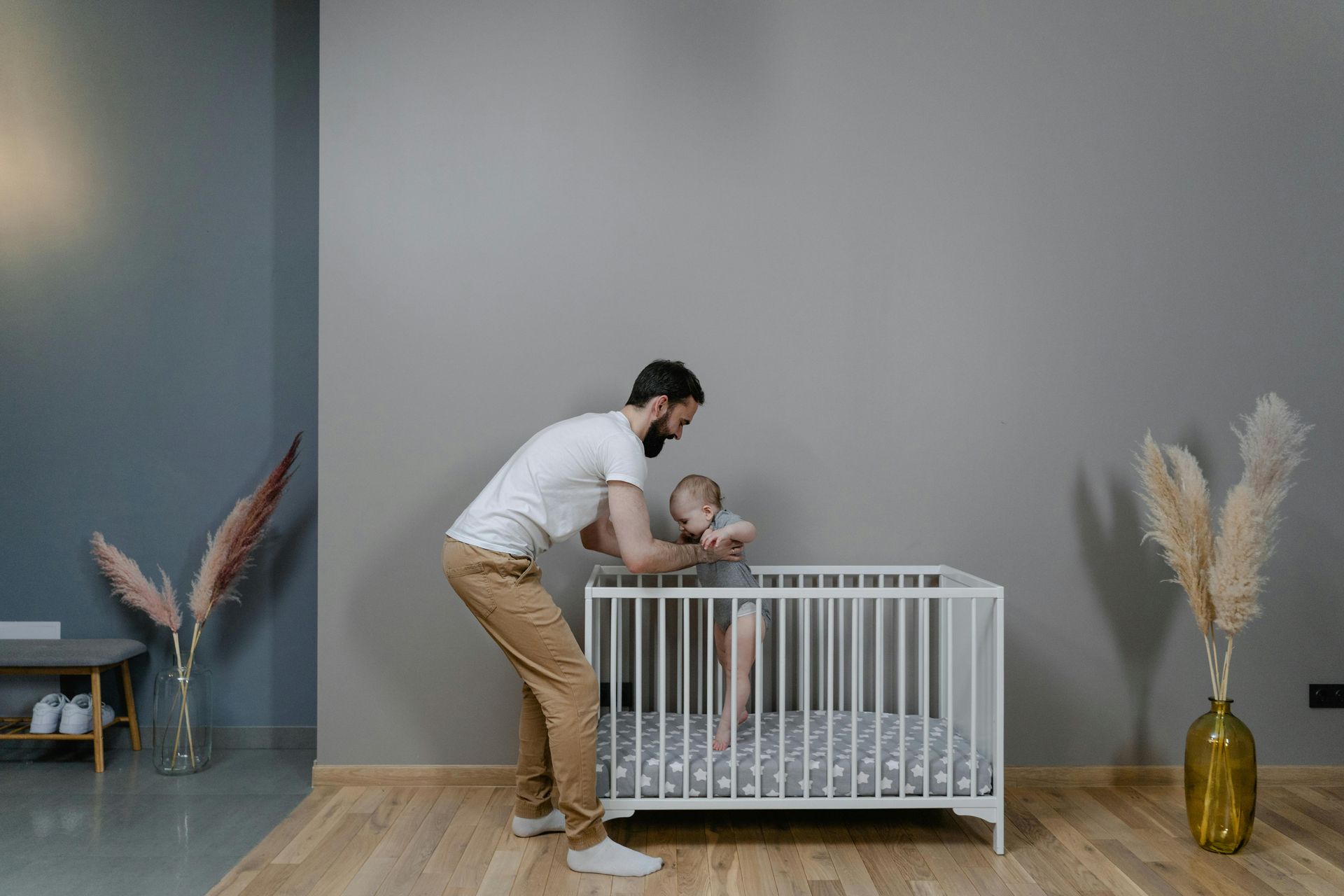 A man is standing next to a crib with a baby in it.