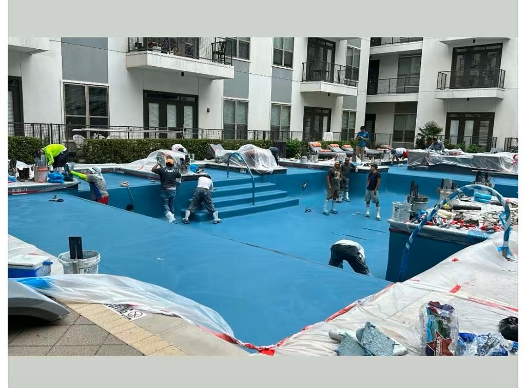 A group of people are painting a swimming pool in front of a building.