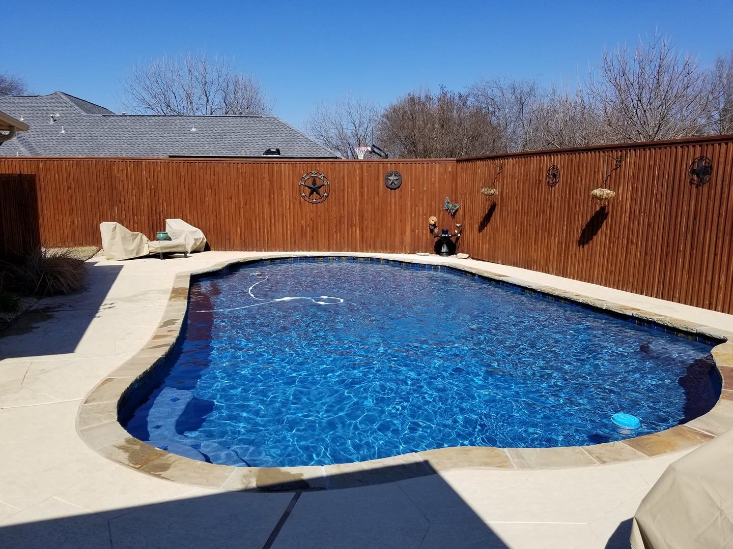 A large swimming pool is surrounded by a wooden fence.