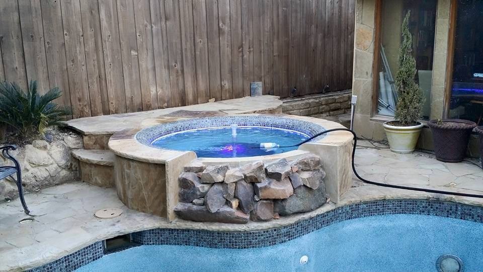 A hot tub is sitting next to a swimming pool.