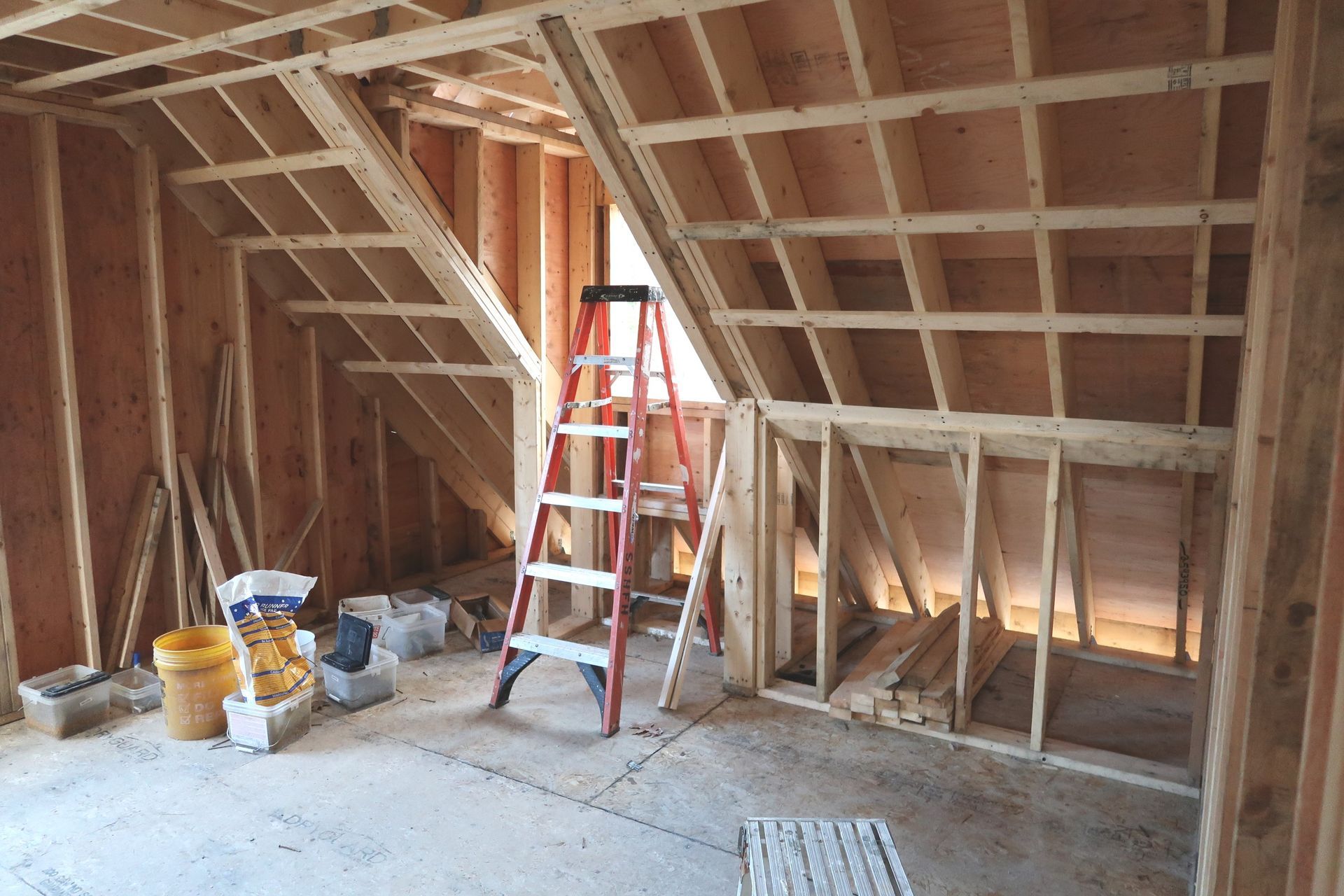 A ladder sits in the middle of a room under construction