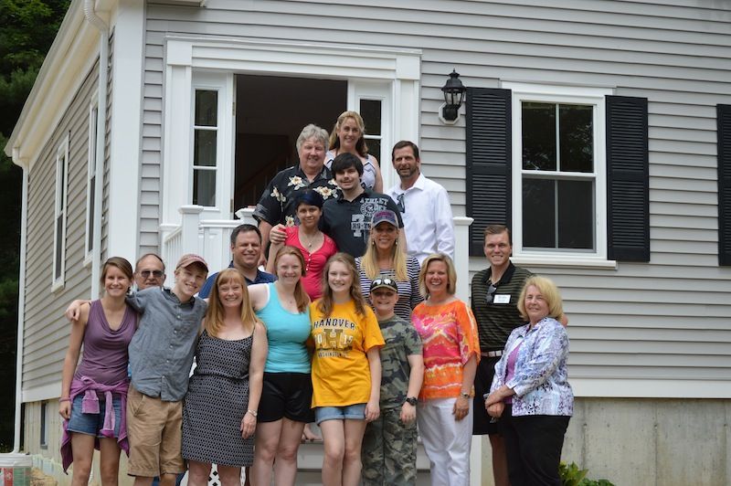 A group of people posing for a picture in front of a house