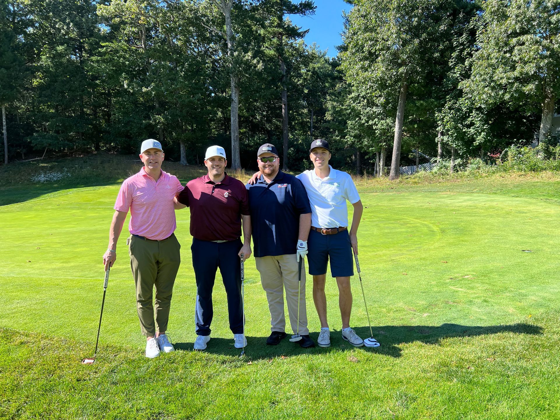 Four men are posing for a picture on a golf course