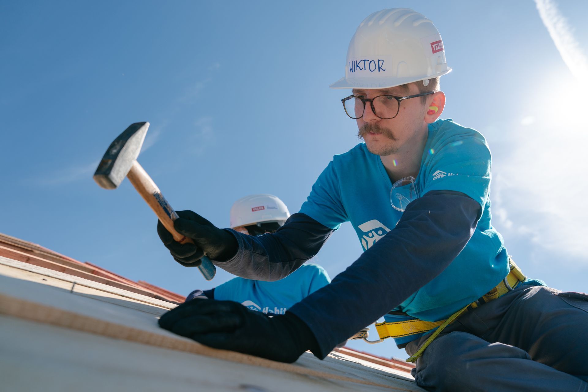 Two construction workers are hugging each other in front of a house.