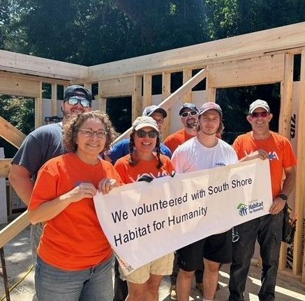 A group of people holding a sign that says we volunteered with south shore habitat for humanity