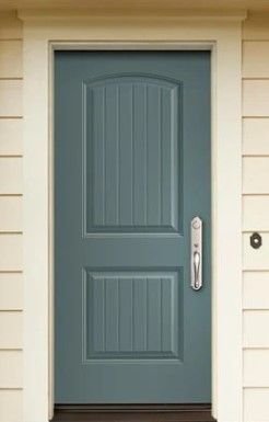 A blue door with a white trim is on a white house.