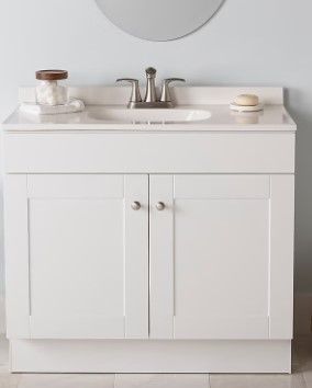 A white bathroom vanity with a sink and a mirror.