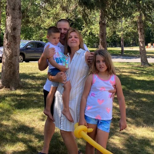 A family posing for a picture in a park with balloons.