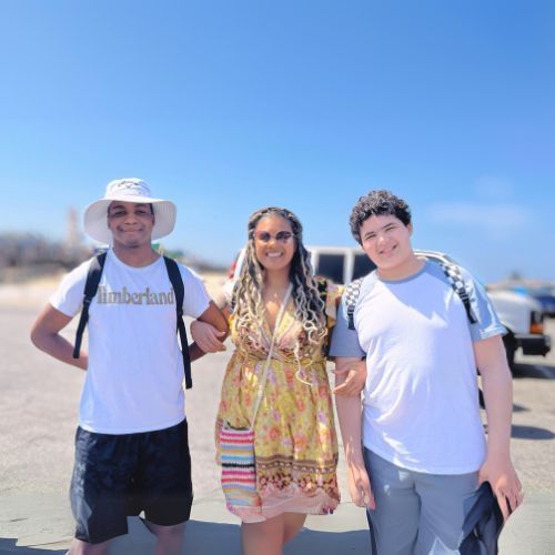 A man wearing a timberland shirt poses with two other people