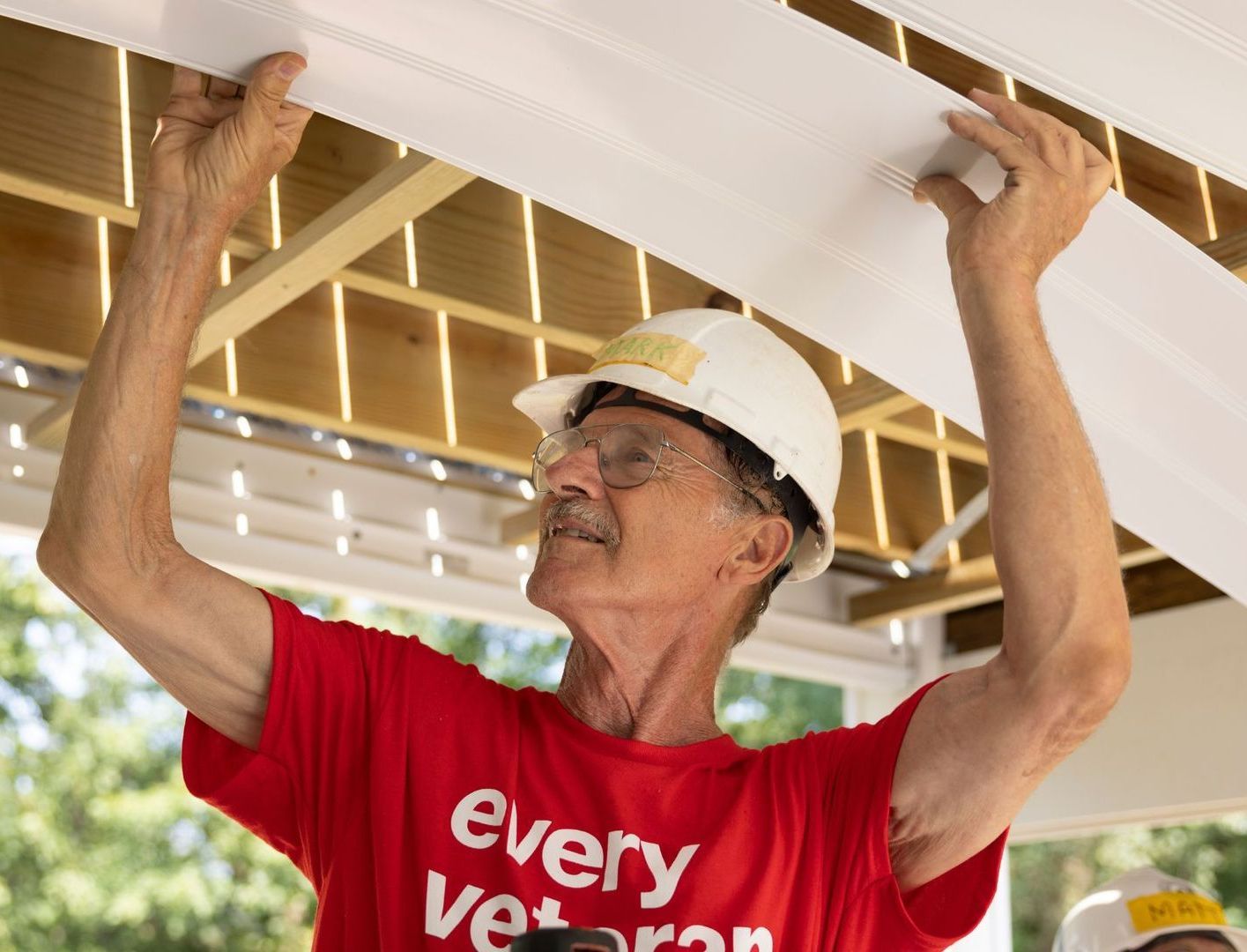 A man wearing a red shirt that says every veteran