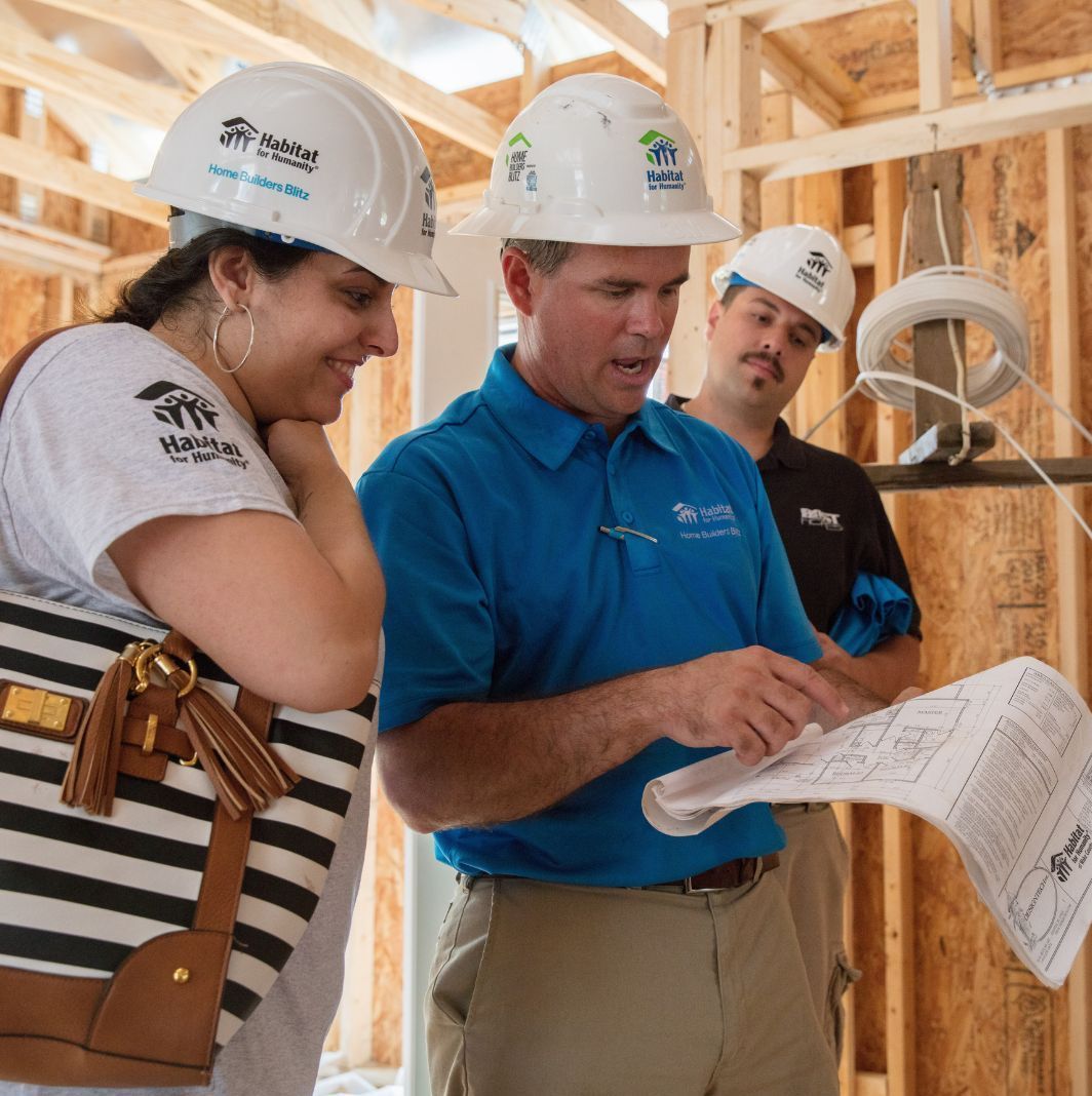 Two men and a woman wearing hard hats with a company logo on them