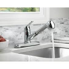 A kitchen sink with a faucet and a bowl of apples on the counter.