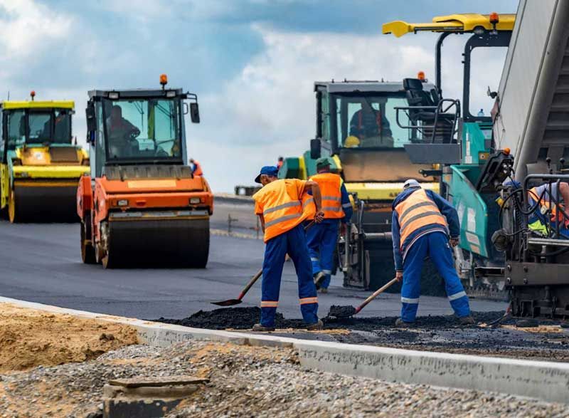 a group of construction workers are working on a road .