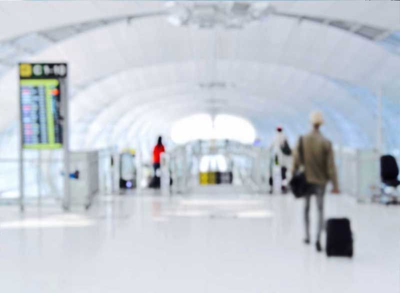 a blurry picture of people walking through an airport with luggage .