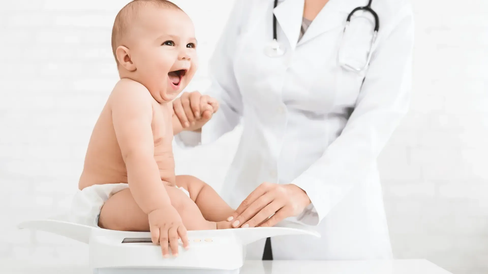 Un bébé est assis sur une balance pendant qu'un médecin regarde.