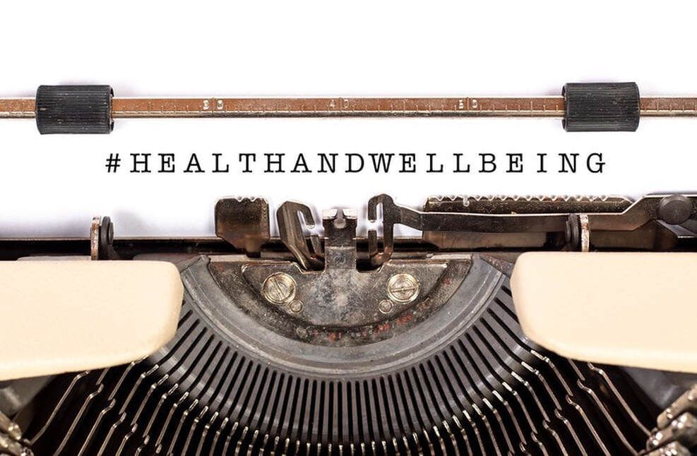 Close-up of a vintage typewriter with the hashtag #HEALTHANDWELLBEING typed on paper.