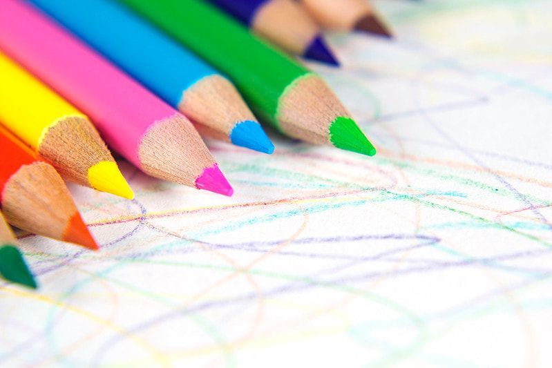 Close-up of colorful pencils on a paper with crayon scribbles.