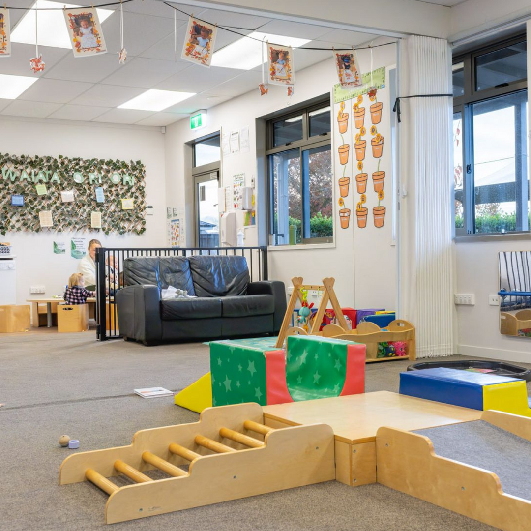 Childcare room with play area, sofa, and decorations.