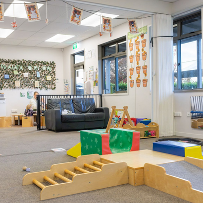 Childcare room with play area, sofa, and decorations.