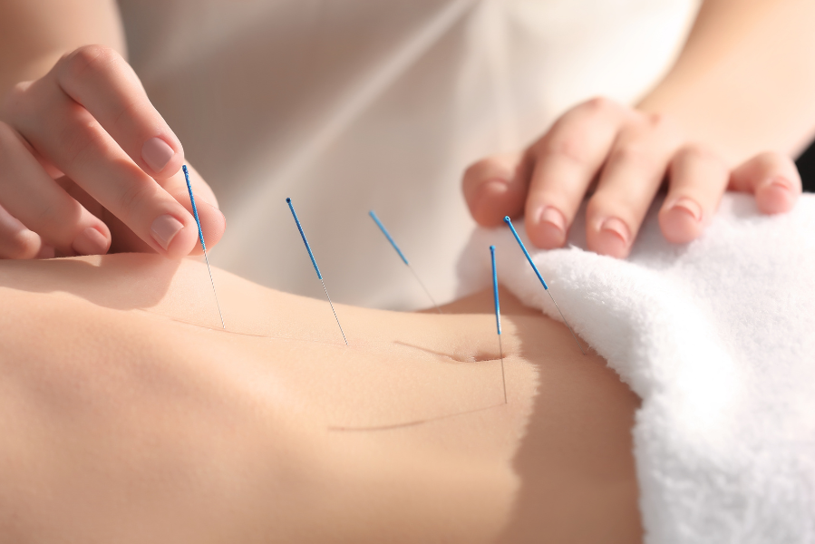 Two cocktails in stemmed glasses on a weathered wooden table, garnished with fruit and ice, straws inserted.