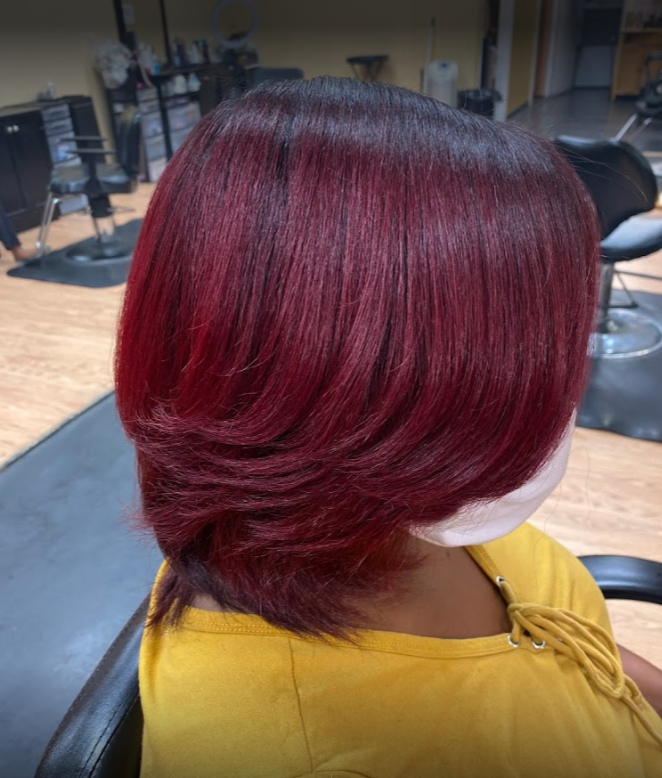 Woman with layered, burgundy-colored bob haircut, wearing a yellow shirt.