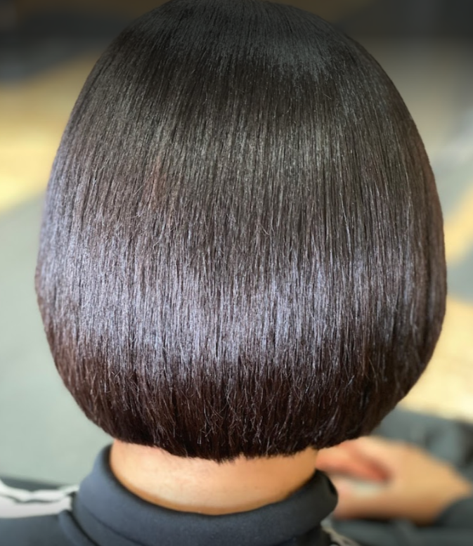 Close-up of a woman's glossy, dark brown, chin-length bob haircut.