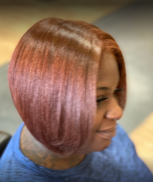 Woman with short, auburn bob haircut. She has a slight smile, is wearing a blue shirt.