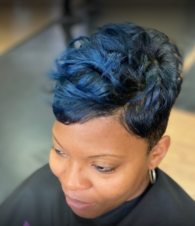 Woman with short, blue-dyed hair, pixie cut. She's smiling slightly.