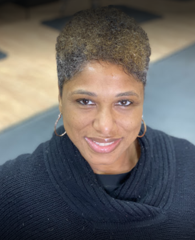 Woman with short, salt-and-pepper hair smiles, wearing gold hoops and a black sweater.