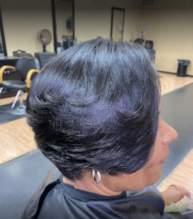 Woman with a layered black bob in a salon, seated.