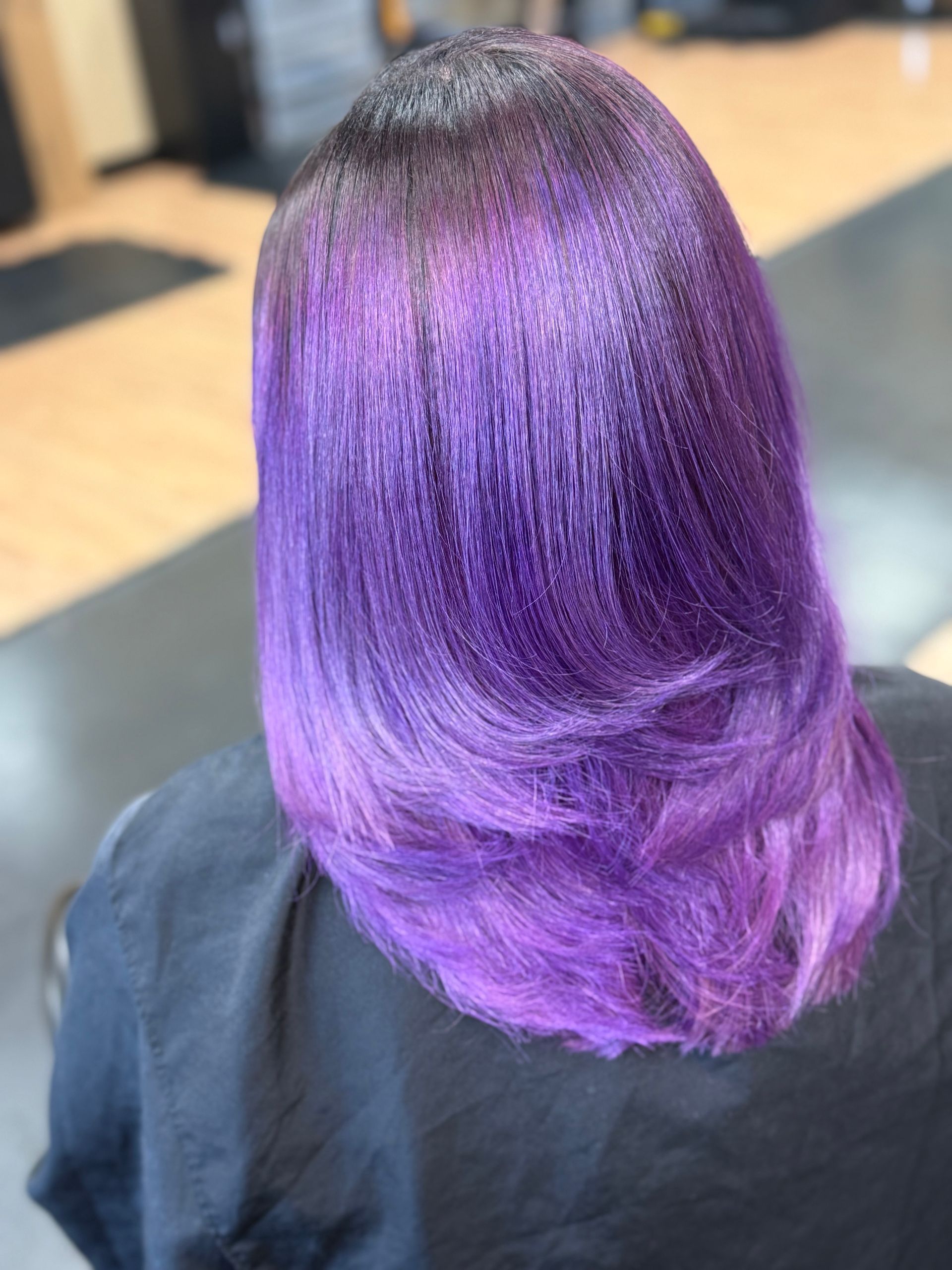 Woman with purple ombre hair, layered, angled bob.
