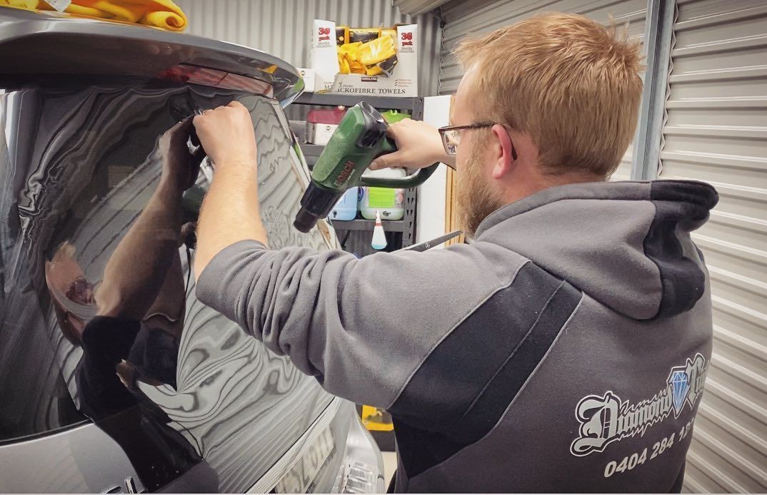 A Man is Installing Tint in a Car — Diamond Tints In Tuggeranong, ACT