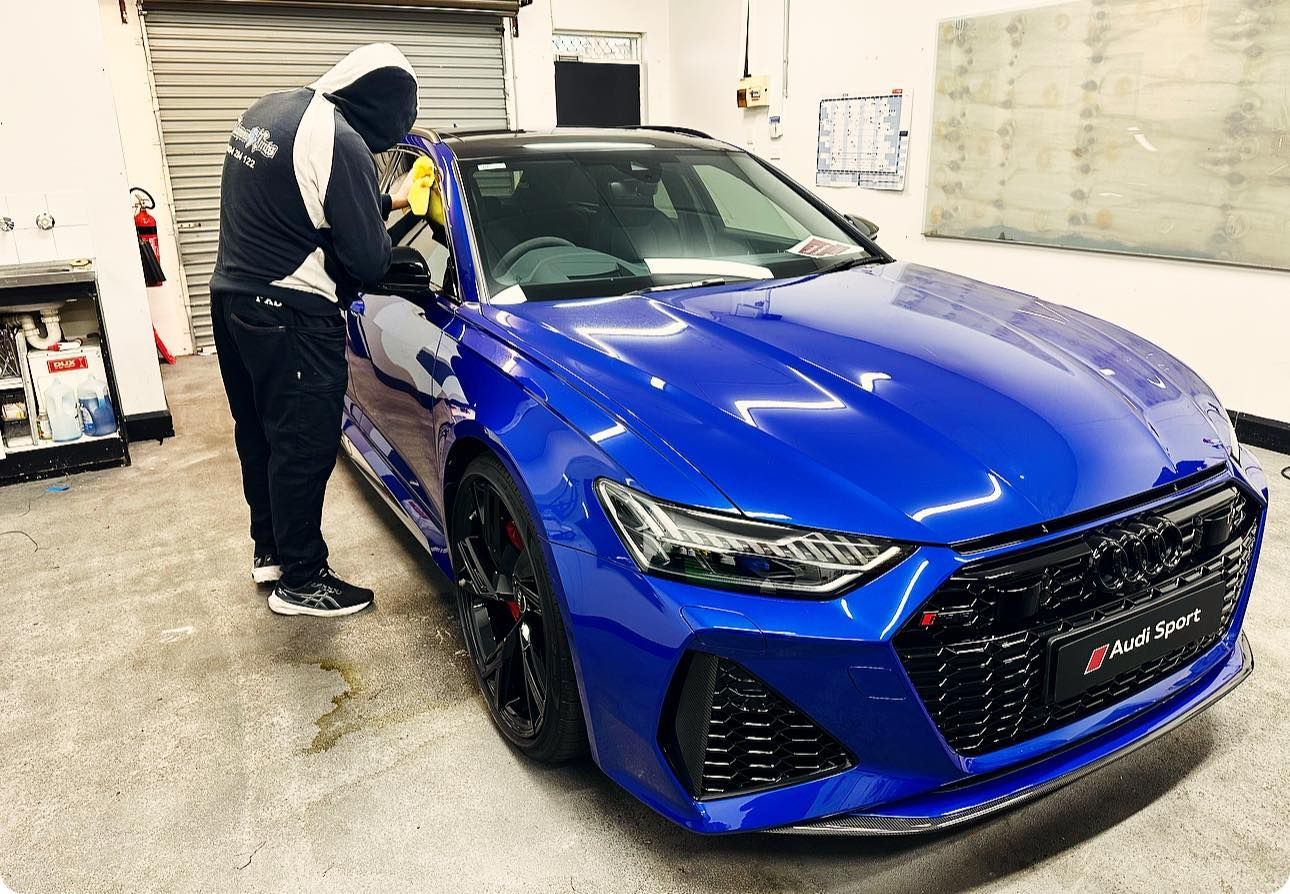 A Man is Polishing a Blue Car in a Garage —	Diamond Tints In Phillip, ACT