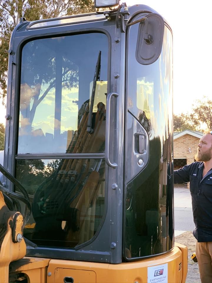 A Man is Standing in Front of a Construction Vehicle — Diamond Tints In Tuggeranong, ACT— Diamond Tints In Tuggeranong, ACT