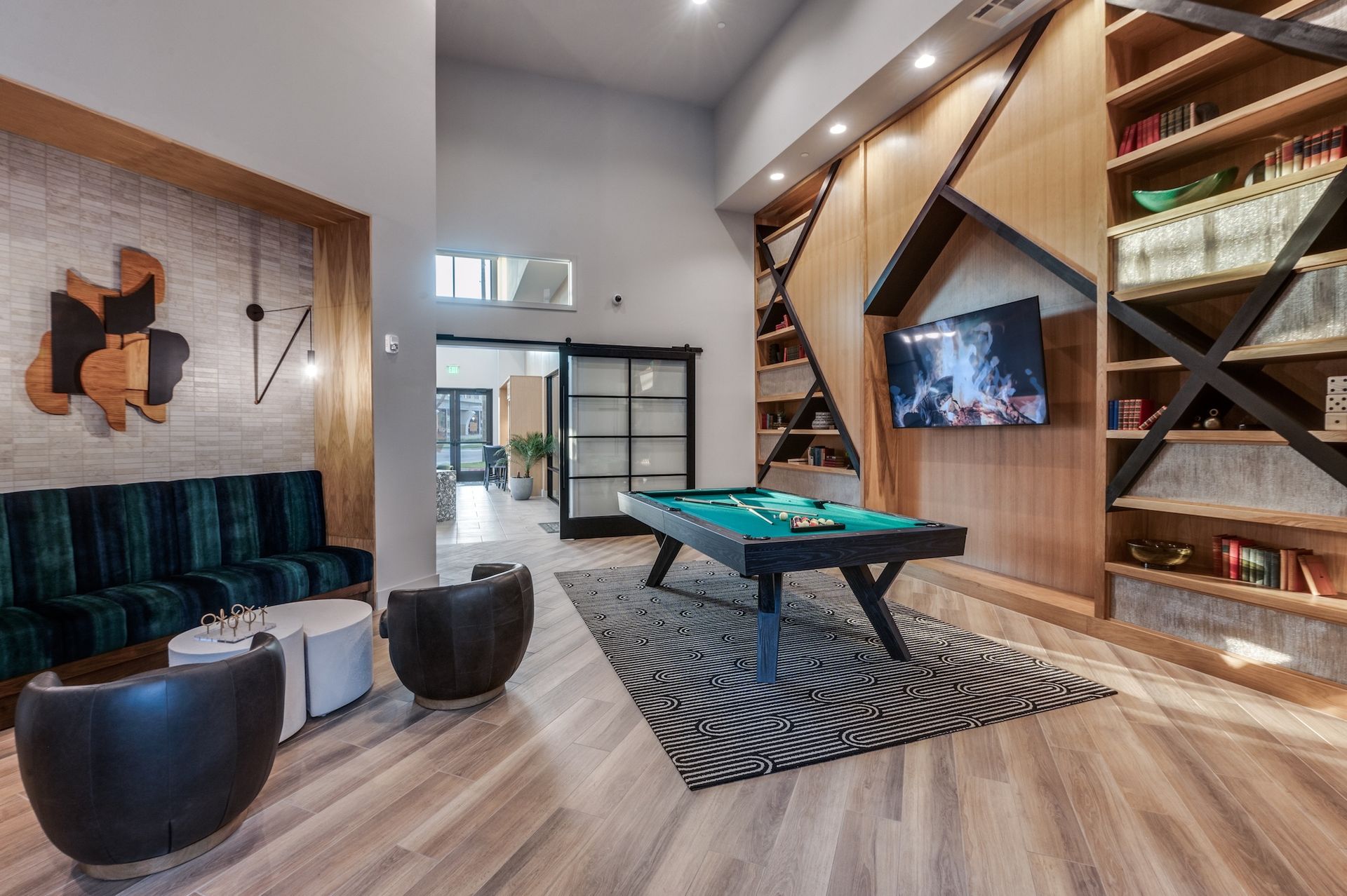 Lounge area with pool table, bookshelves, seating, and geometric wood paneling.