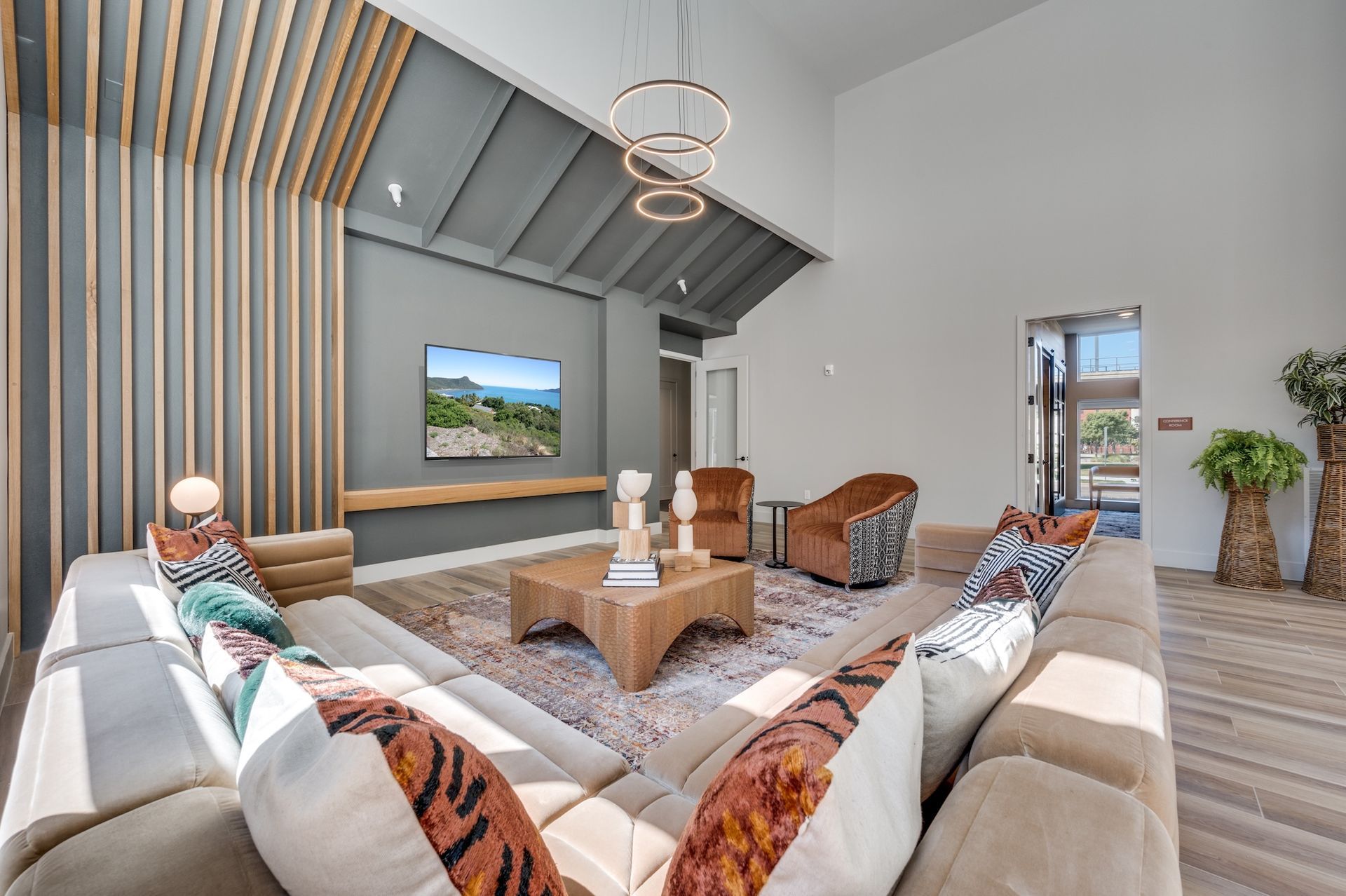 Modern living room with sectional sofa, decorative pillows, and accent chairs; TV on gray wall.