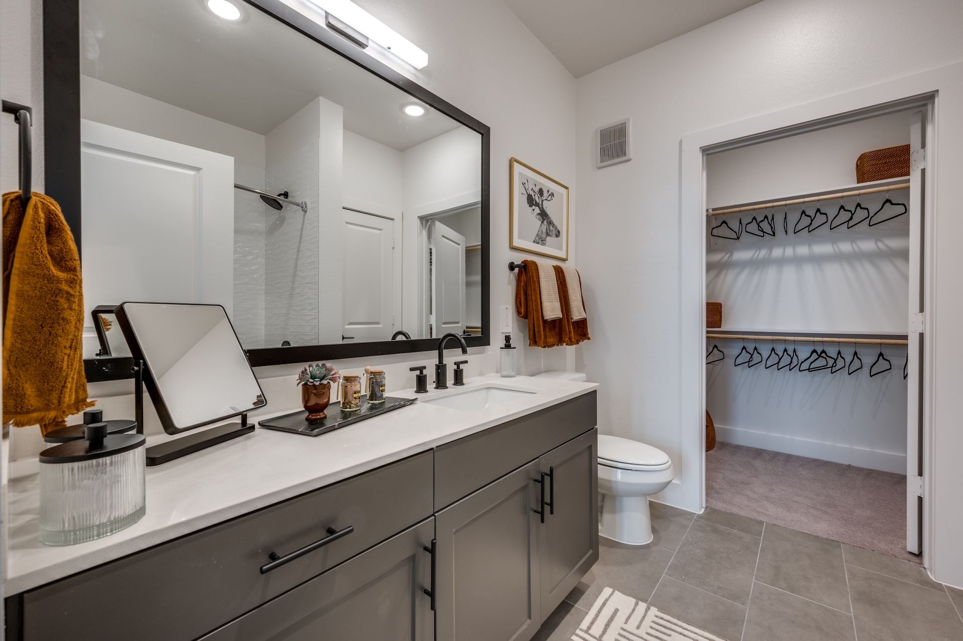 Bathroom with gray vanity, large mirror, and open closet.