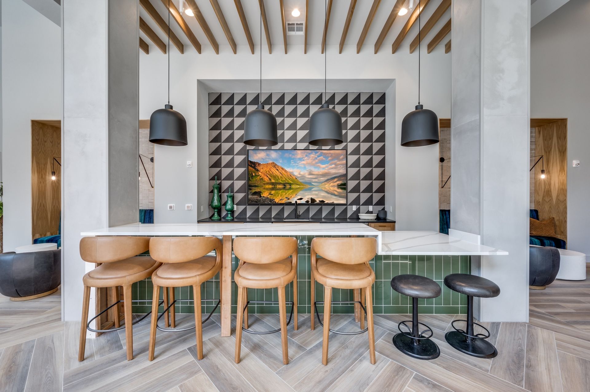 Bar area with stools, geometric tile wall, and overhead pendant lights.
