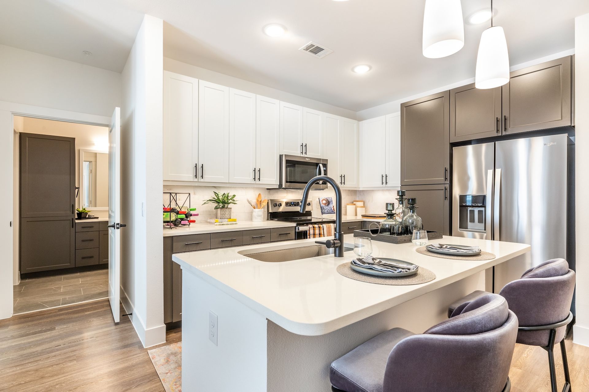 Modern kitchen with white and gray cabinets, stainless steel appliances, and a breakfast bar.