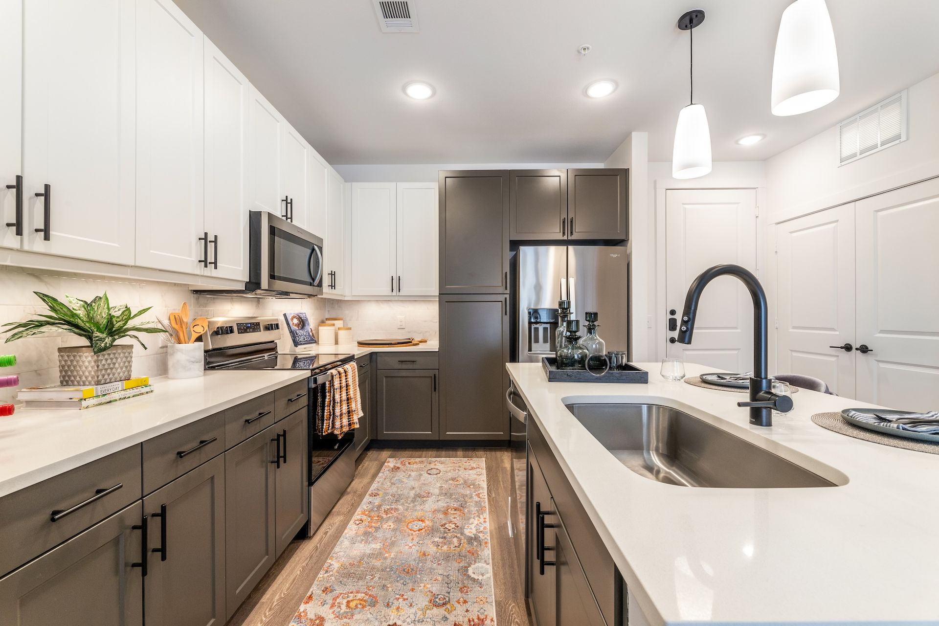 Modern kitchen with white and gray cabinets, stainless steel appliances, and a central island with sink.